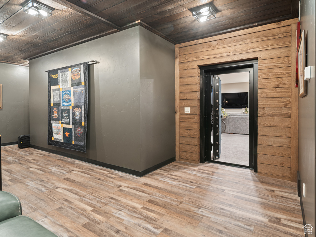 Corridor with wood finished floors, wooden ceiling, baseboards, and ornamental molding