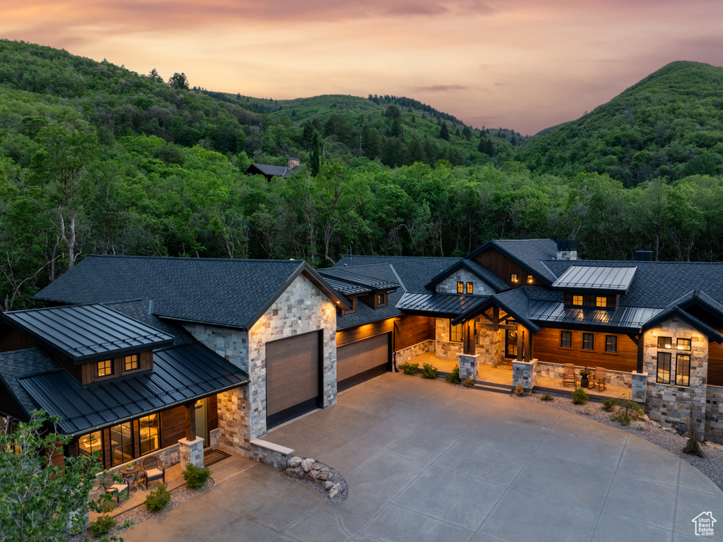 Modern home with a standing seam roof, metal roof, a forest view, and stone siding