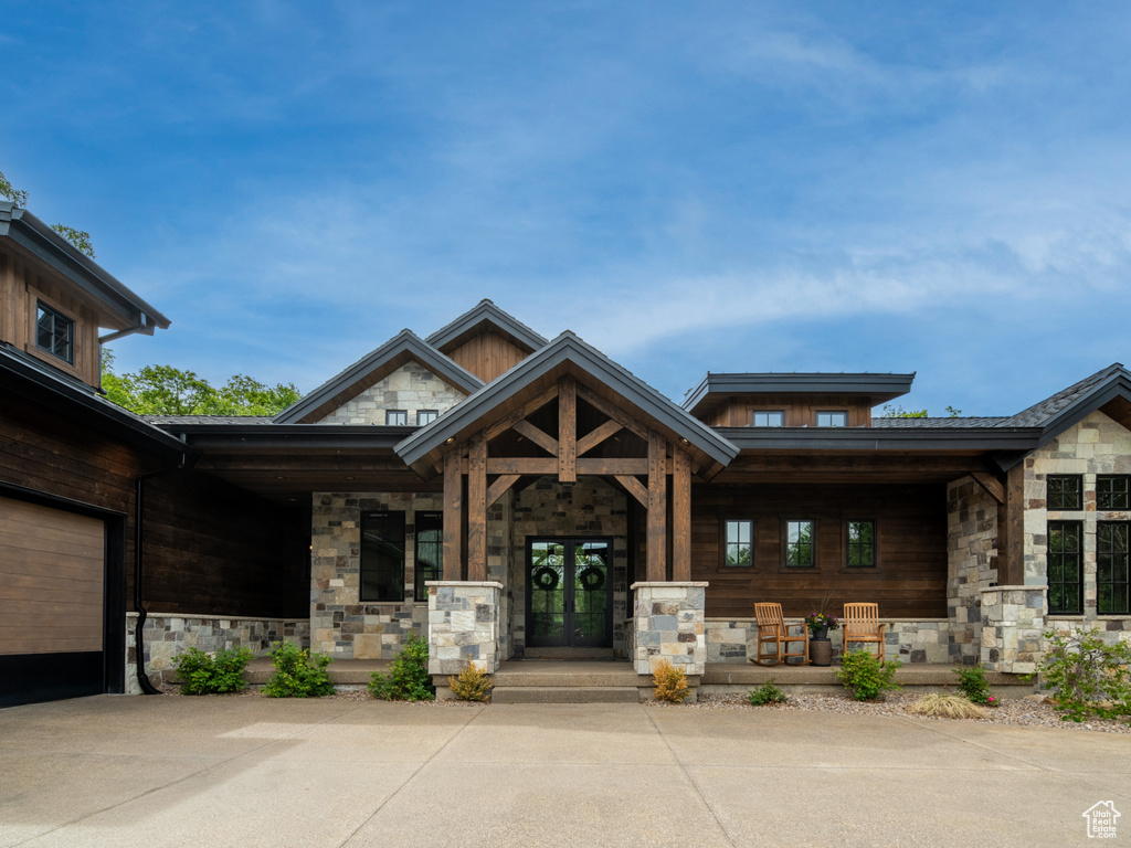 View of exterior entry with covered porch and stone siding