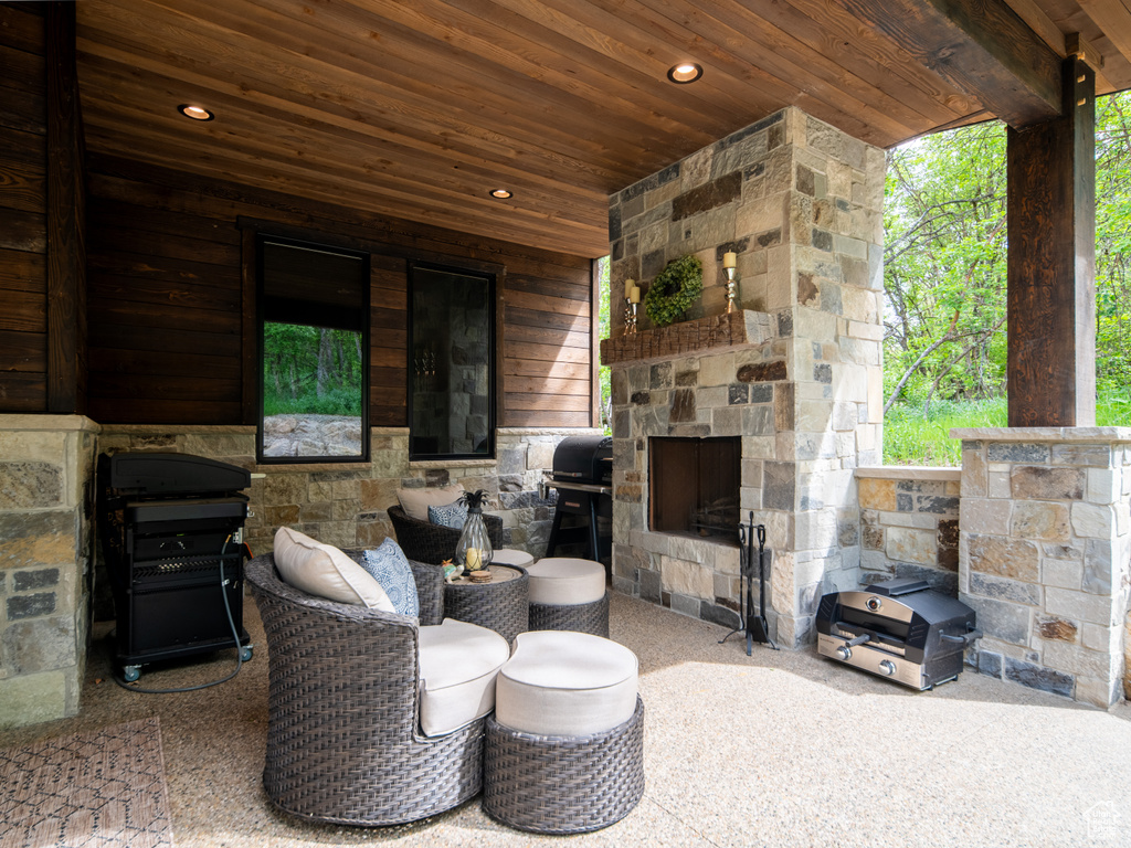 View of patio featuring an outdoor stone fireplace and a grill