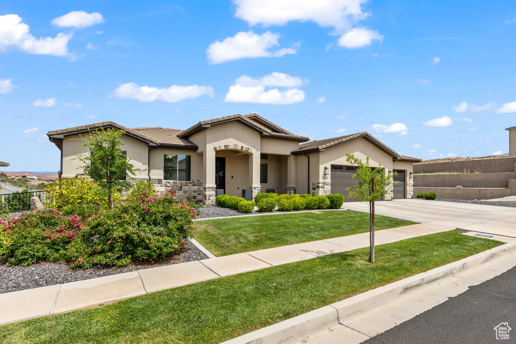 View of front of property with an attached garage, concrete driveway, stucco siding, stone siding, and a tile roof