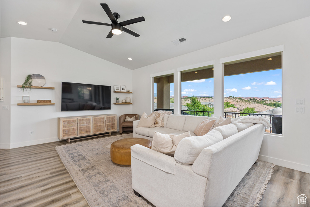 Living area with wood finished floors, a ceiling fan, lofted ceiling, baseboards, and recessed lighting
