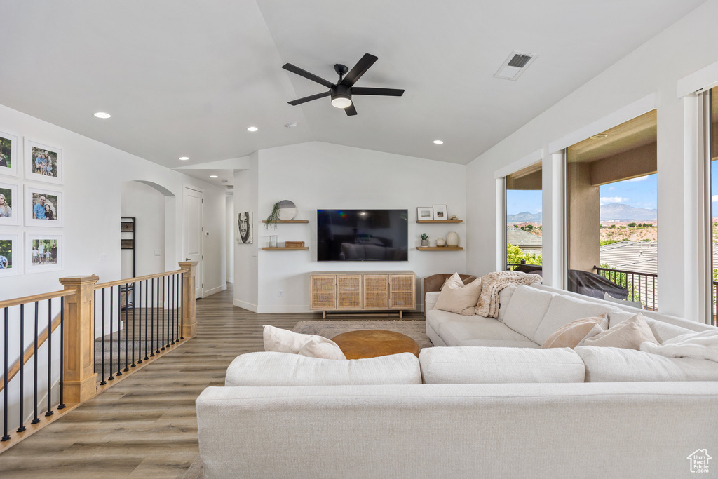 Living area featuring wood finished floors, lofted ceiling, a ceiling fan, arched walkways, and recessed lighting