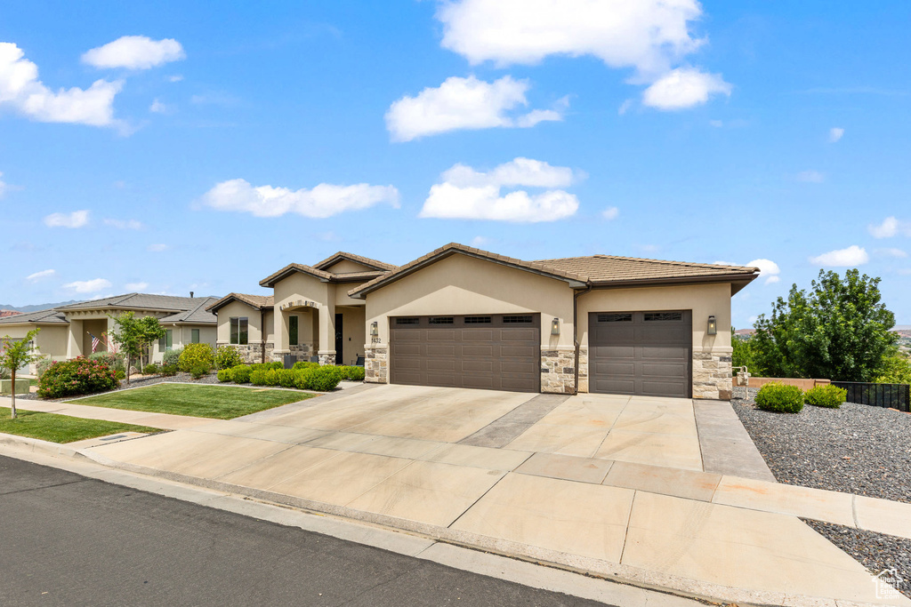 View of front of home featuring stucco siding, a garage, stone siding, and concrete driveway
