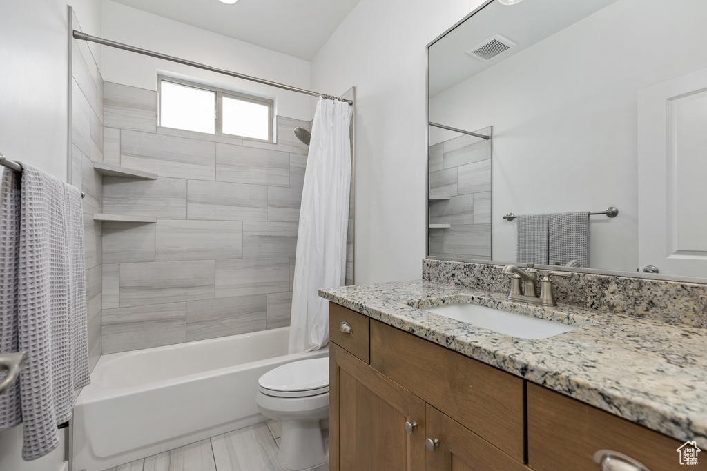 Bathroom with vanity, shower / bath combination with curtain, and toilet