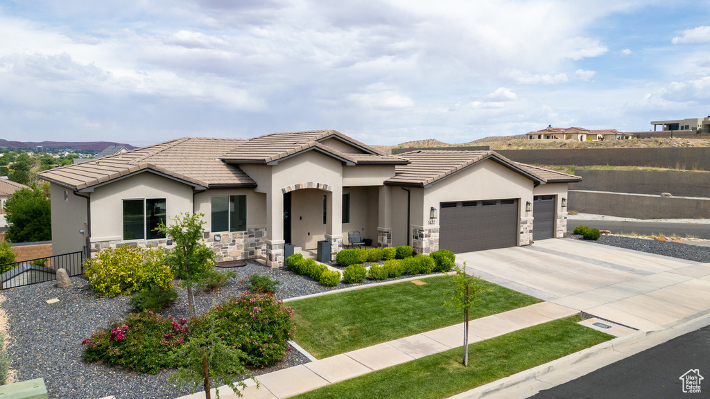 View of front facade with stone siding, an attached garage, stucco siding, and concrete driveway