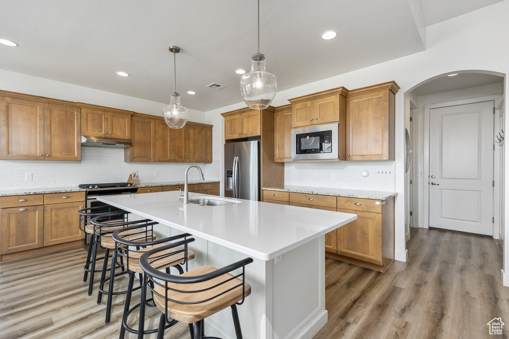 Kitchen with a sink, built in microwave, stainless steel fridge, arched walkways, and stove