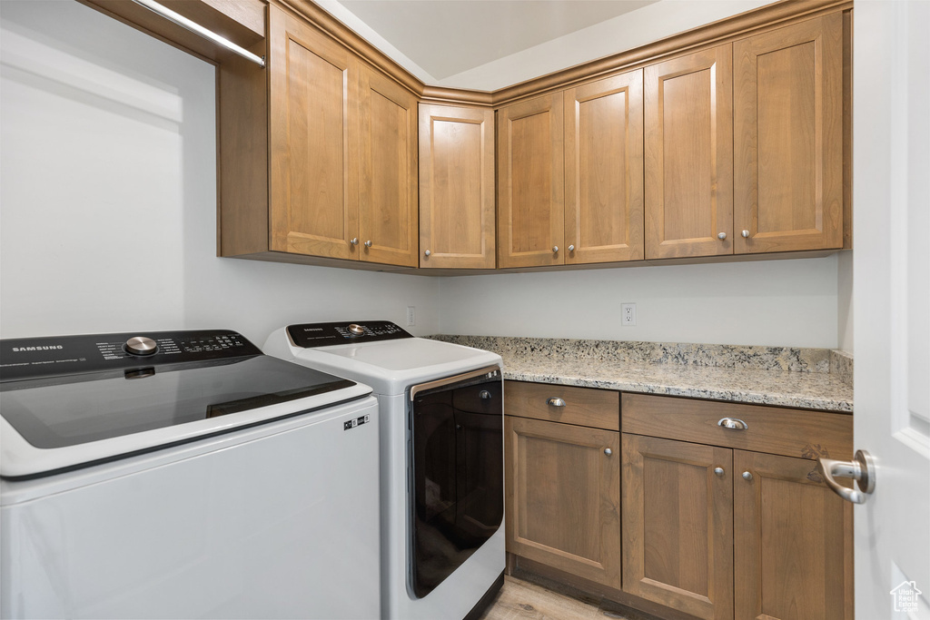 Laundry room featuring cabinet space, washing machine and clothes dryer, and light wood finished floors