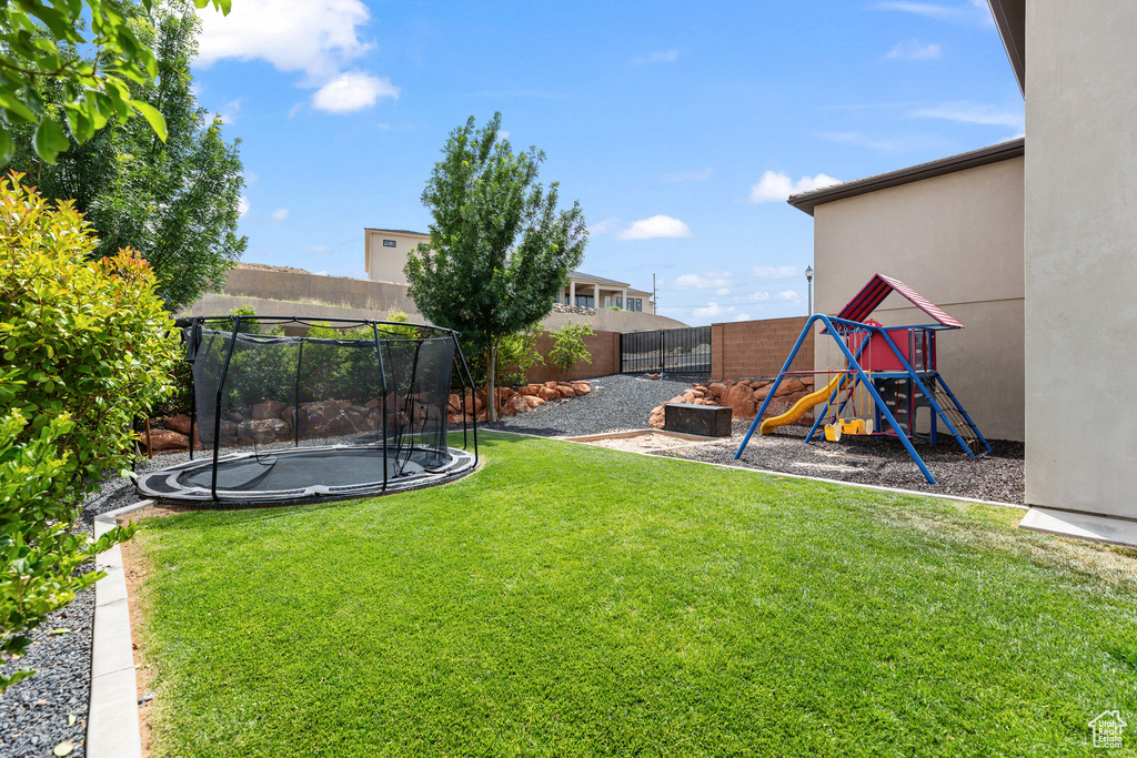 View of yard with a trampoline and a playground