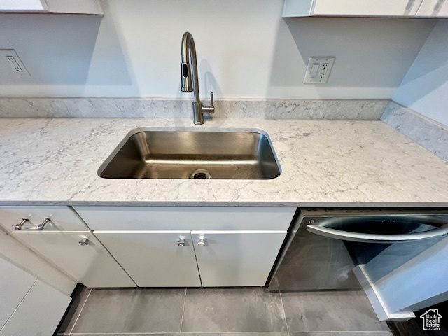 Kitchen view of a sink, light stone counters, and white cabinets