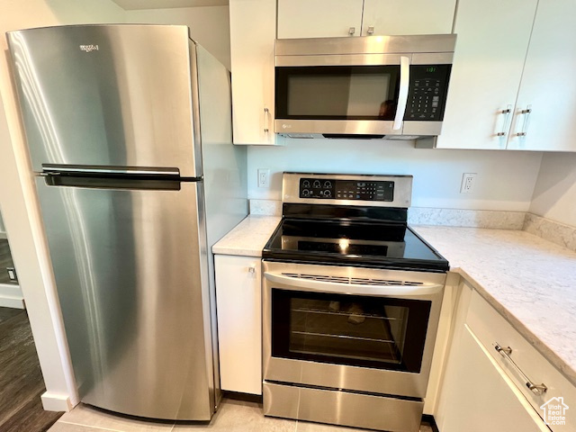 Kitchen with stainless steel appliances, white cabinets, and light wood-style floors