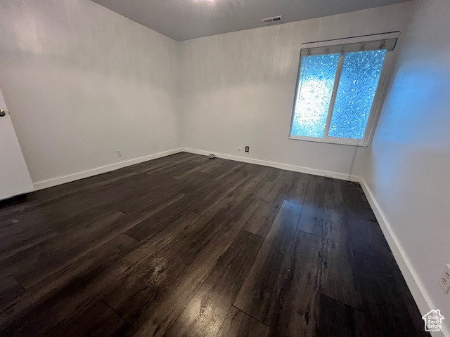 Empty room with dark wood-style floors and baseboards