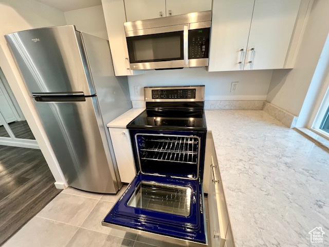 Kitchen featuring appliances with stainless steel finishes, light countertops, white cabinetry, and light tile patterned floors