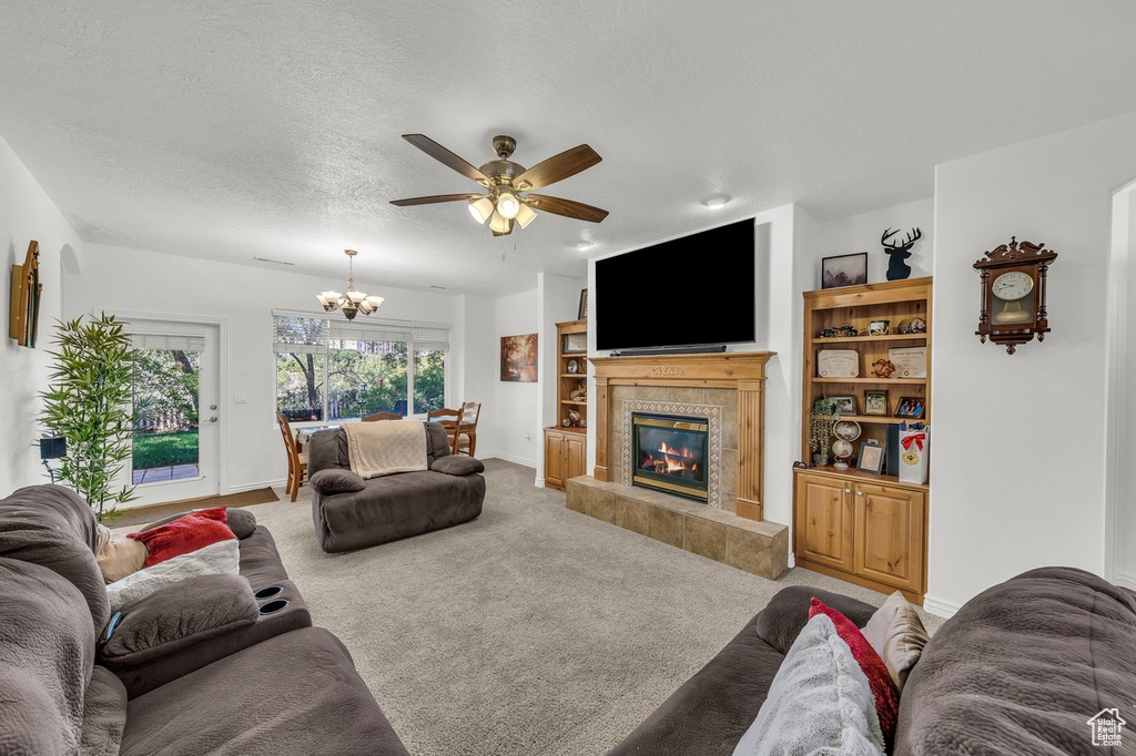 Living area featuring a chandelier, carpet floors, ceiling fan, a tile fireplace, and baseboards