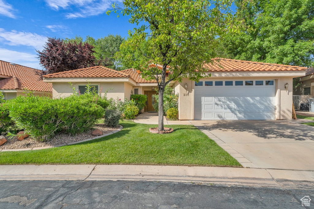 Mediterranean / spanish home featuring stucco siding, a tile roof, an attached garage, and driveway