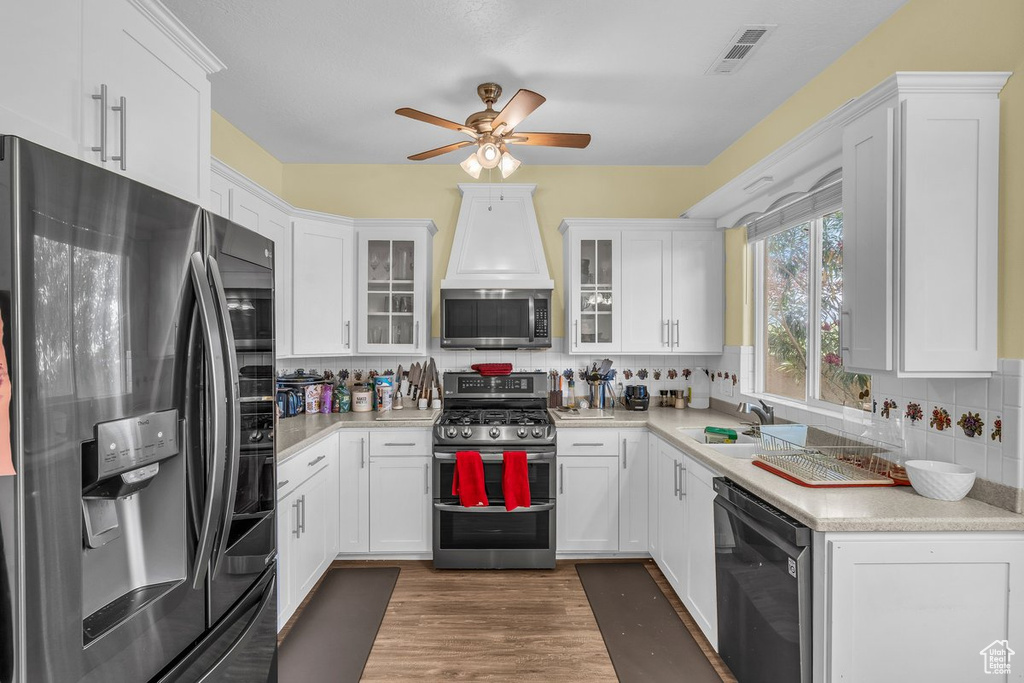 Kitchen with appliances with stainless steel finishes, a sink, ceiling fan, tasteful backsplash, and light countertops