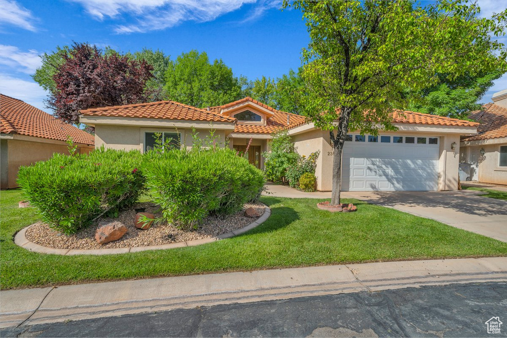 Mediterranean / spanish home featuring stucco siding, an attached garage, concrete driveway, a tile roof, and a front yard
