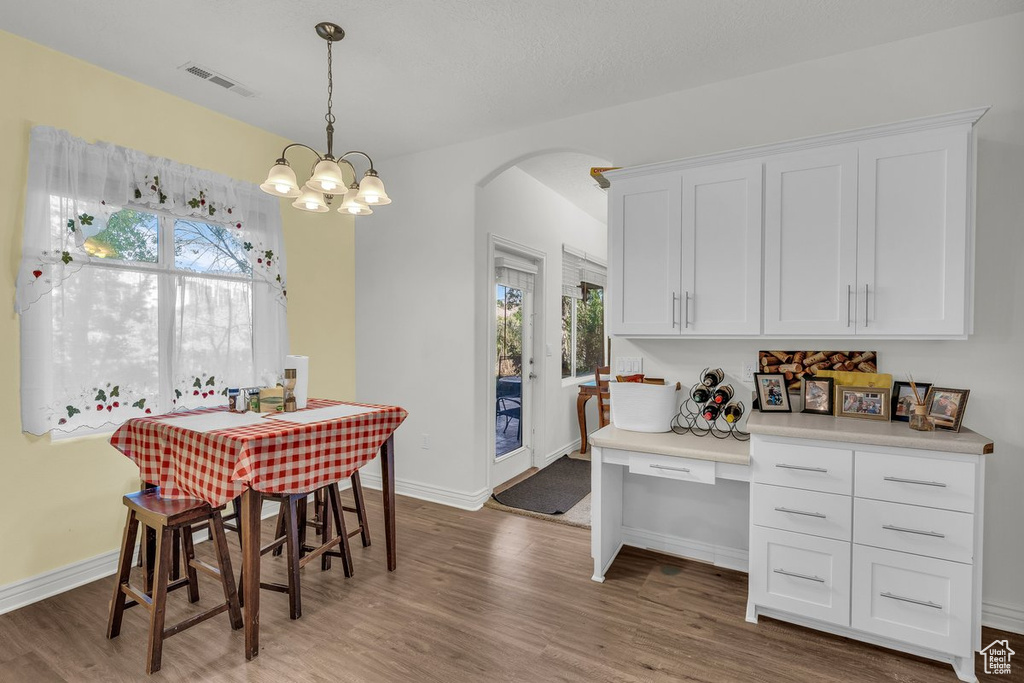 Dining area featuring arched walkways, wood finished floors, baseboards, and a chandelier