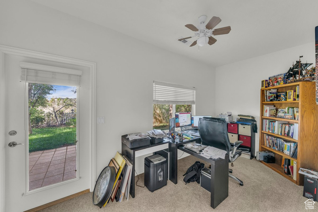 Carpeted home office with a ceiling fan