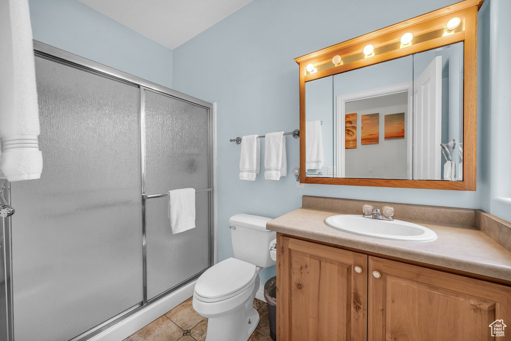 Bathroom featuring vanity, toilet, a shower stall, and tile patterned floors
