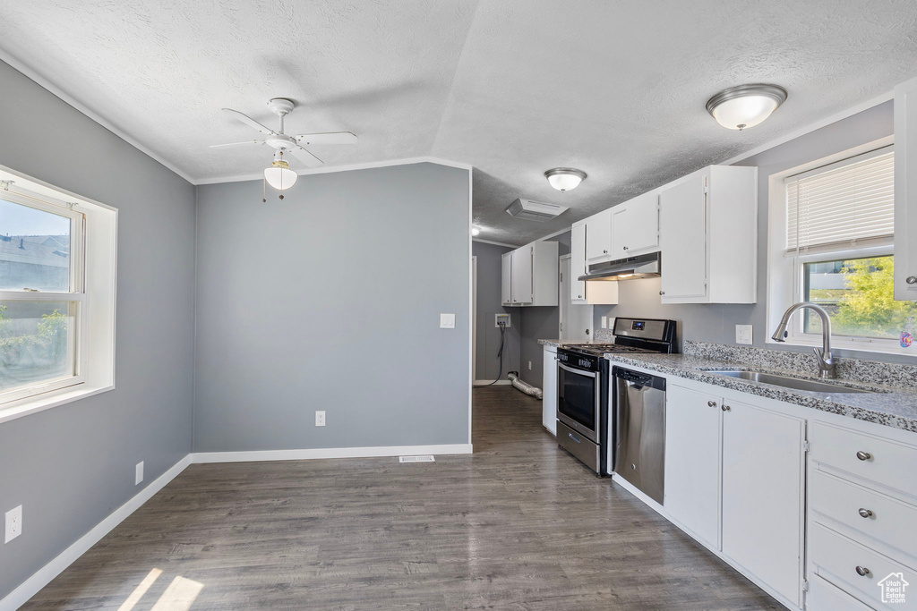 Kitchen with appliances with stainless steel finishes, a sink, under cabinet range hood, ceiling fan, and a textured ceiling