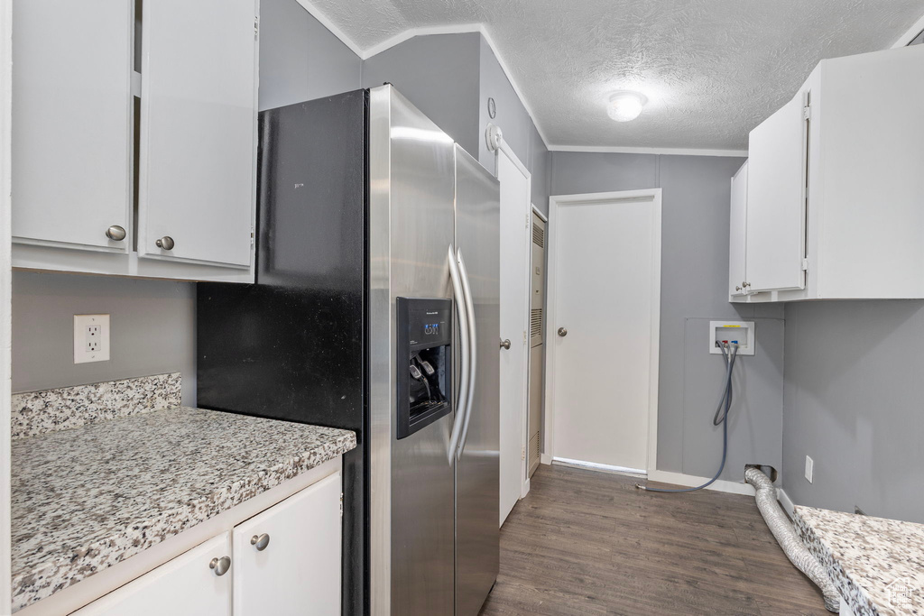 Kitchen with stainless steel refrigerator with ice dispenser, dark wood-type flooring, white cabinets, a textured ceiling, and baseboards