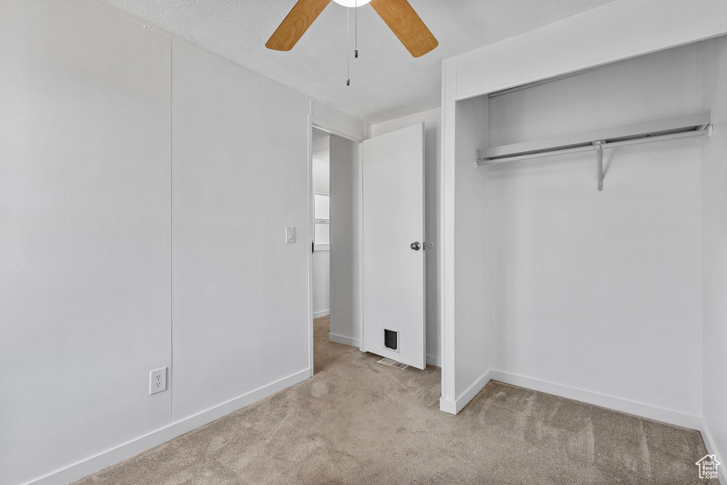 Unfurnished bedroom with carpet, baseboards, a closet, and a ceiling fan
