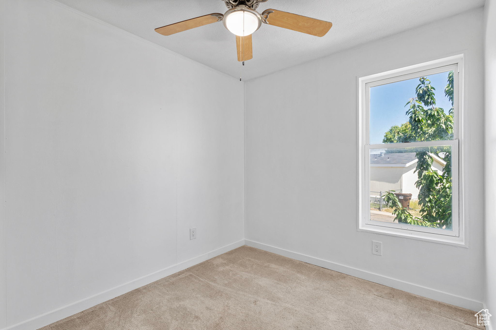 Empty room with light carpet, baseboards, and ceiling fan