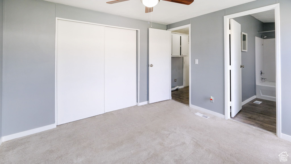 Unfurnished bedroom featuring carpet, a closet, connected bathroom, and ceiling fan