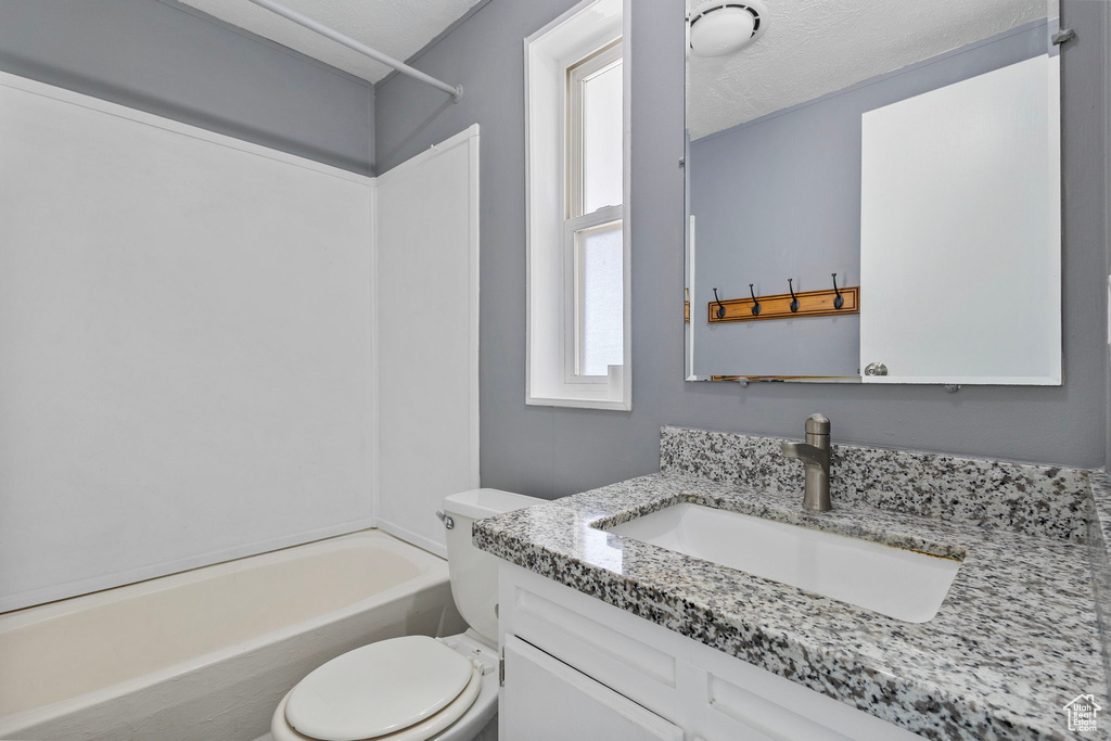 Bathroom featuring toilet, vanity, and washtub / shower combination