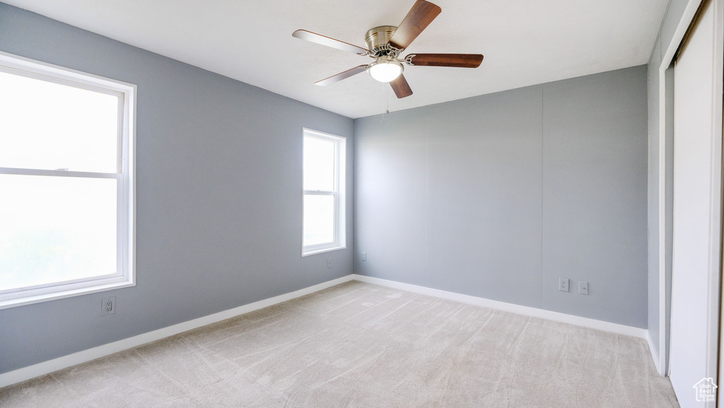 Empty room with light carpet and a ceiling fan