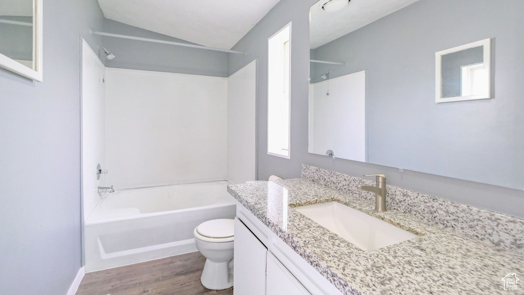 Bathroom with vanity, wood finished floors, vaulted ceiling, and shower / bath combination