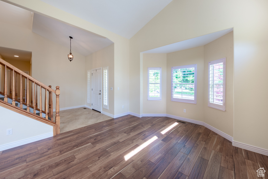 Foyer with stairway, wood finished floors, high vaulted ceiling, and baseboards