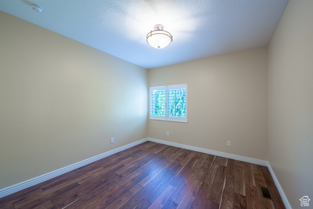 Unfurnished room with dark wood finished floors, a smoke detector, and baseboards