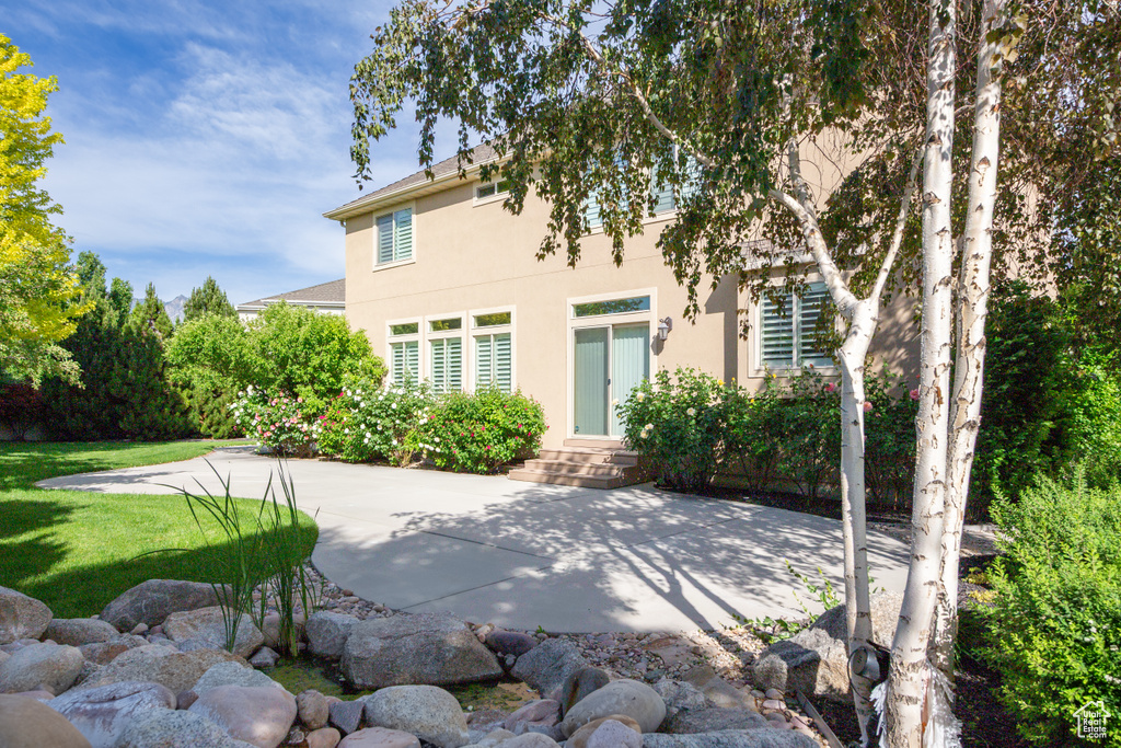 Rear view of property with stucco siding, a yard, and a patio area
