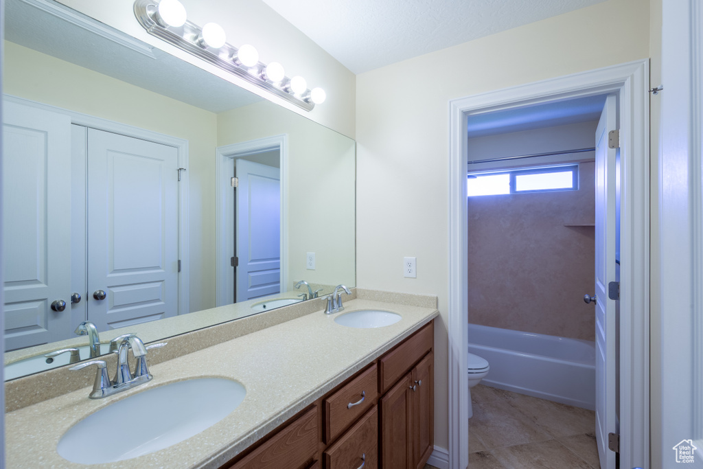 Full bathroom with toilet, double vanity, and tile patterned floors