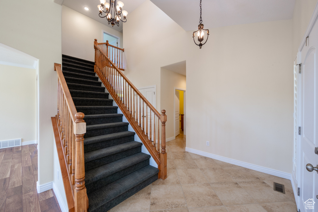 Stairway featuring a chandelier, baseboards, and a towering ceiling