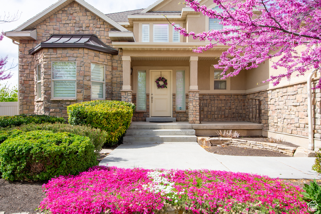 View of exterior entry featuring stone siding, stucco siding, and a porch