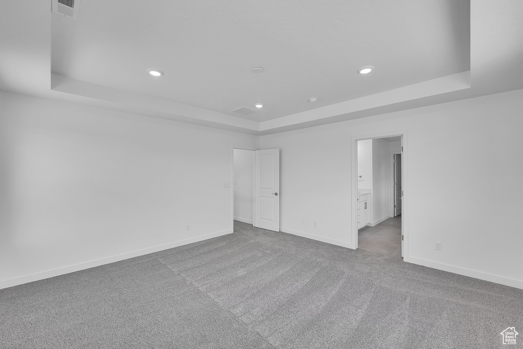 Spare room with a tray ceiling, carpet flooring, recessed lighting, and baseboards