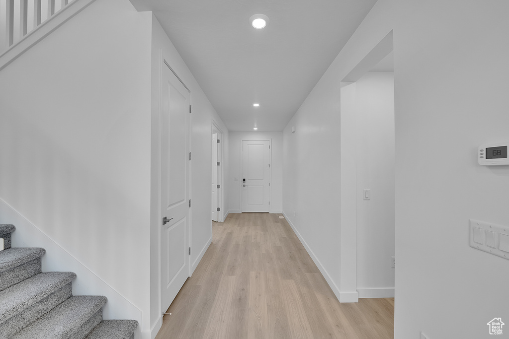 Corridor with recessed lighting, light wood-style floors, baseboards, and stairs
