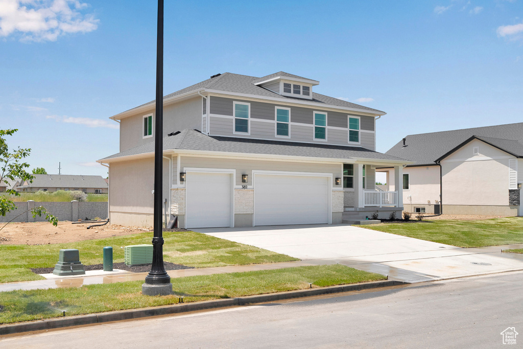 Traditional style home featuring driveway, an attached garage, and roof with shingles
