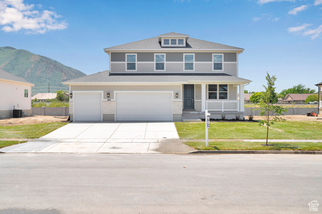 View of front of home with covered porch, concrete driveway, a mountain view, roof with shingles, and central air condition unit