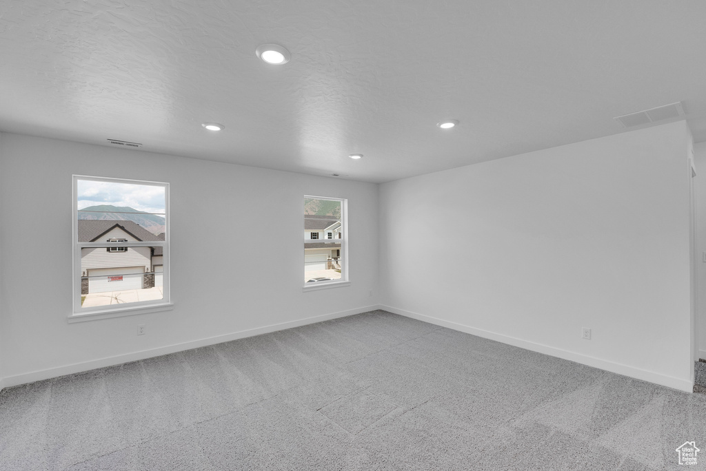 Carpeted empty room with recessed lighting and baseboards
