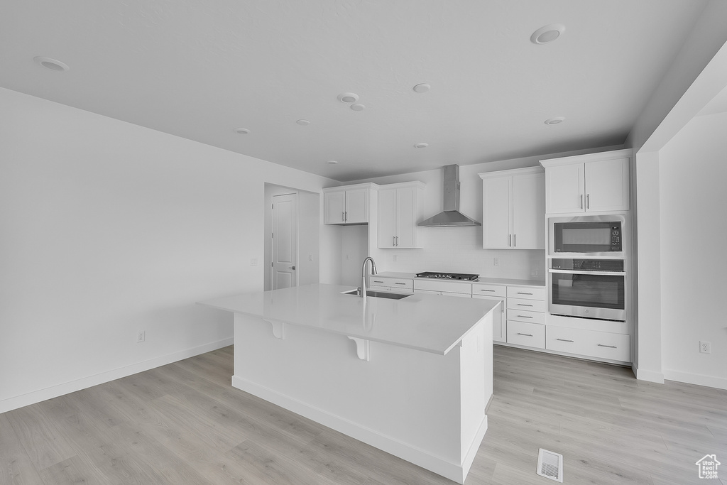 Kitchen featuring stainless steel oven, wall chimney exhaust hood, built in microwave, gas stovetop, and a sink