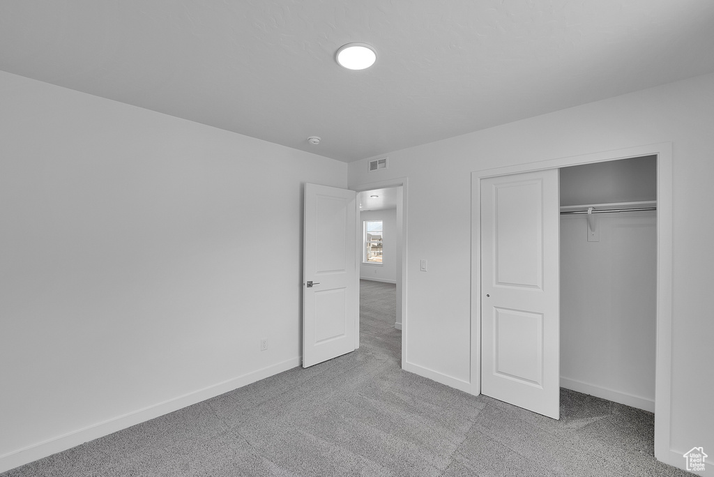 Unfurnished bedroom featuring carpet flooring, baseboards, and a closet