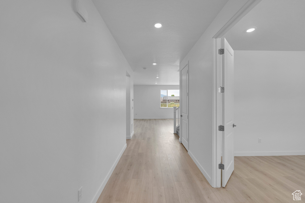 Hallway with light wood-style floors, recessed lighting, and baseboards