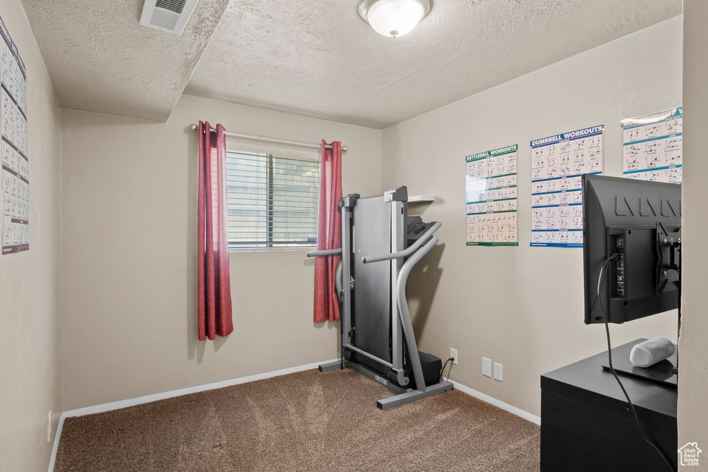Exercise room featuring a textured ceiling, carpet flooring, and baseboards