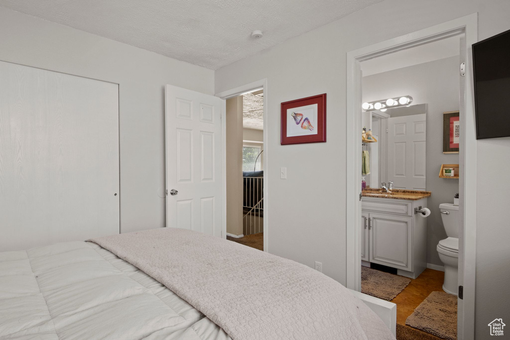 Bedroom featuring ensuite bathroom, a sink, and a closet