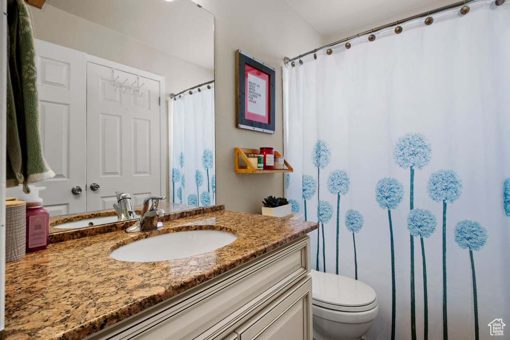 Bathroom with toilet, vanity, and a shower with shower curtain