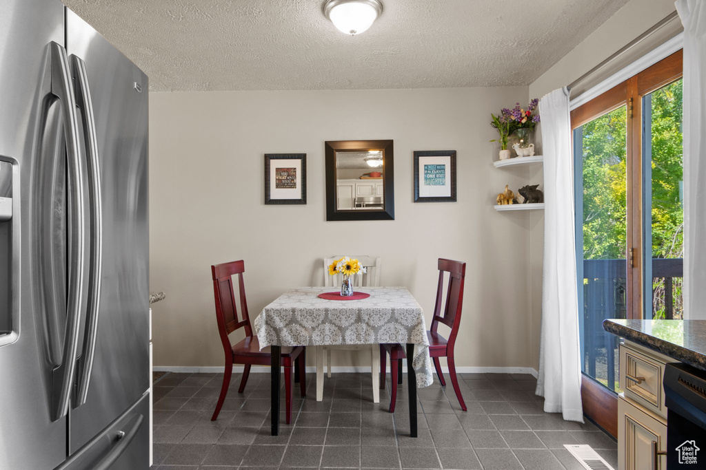 Dining room featuring a textured ceiling, dark tile patterned floors, and baseboards